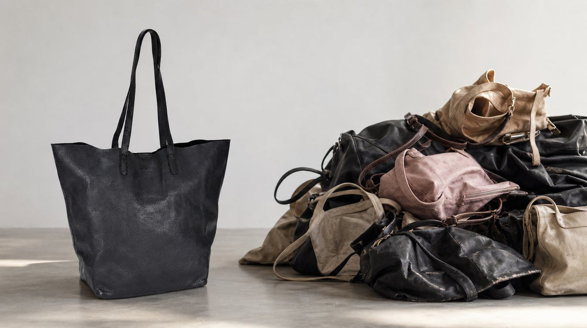 Een goed gemaakte leren tas tegenover een stapel versleten synthetische tassen