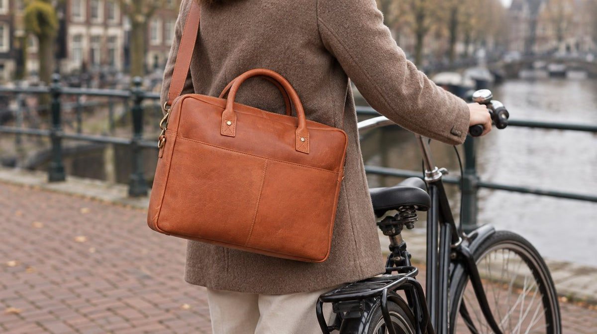 Leren tas schuin over het lichaam gedragen naast een zwarte fiets aan een Nederlandse gracht