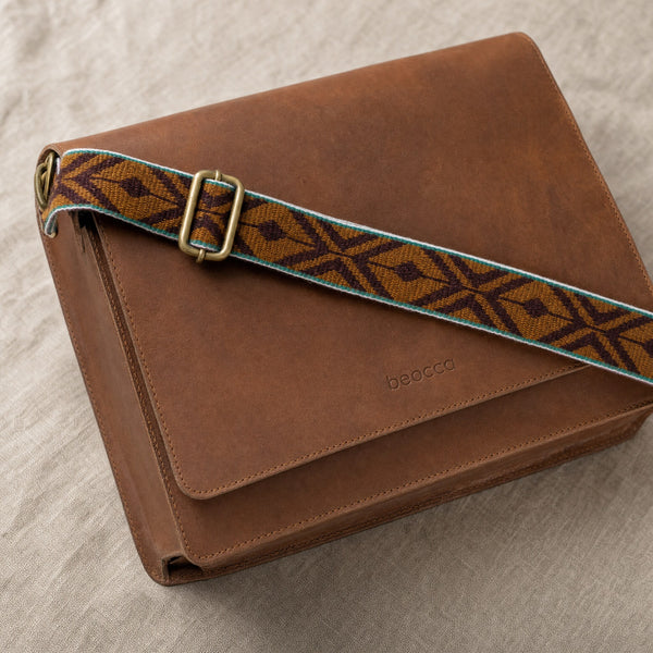 Detail van het cognac leer en de geweven band met ruitmotief van de Beocca Ivy