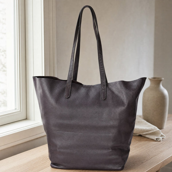 Beocca Mira shopper in donkerbruin leer op een eikentafel bij het raam